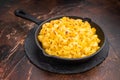 Baked mac and cheese in a black skillet, set against a rustic dark brown background Royalty Free Stock Photo