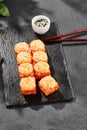 Baked Maki sushi on dark slate. Hot california maki with tobiko. Sushi roll with masago caviar, cheese topped baked oven. Style