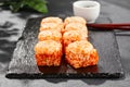 Baked Maki sushi on dark slate. Hot california maki with tobiko. Sushi roll with masago caviar, cheese topped baked oven. Style