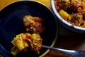 Baked meatball pasta on a black plate with a pasta filled casserole Royalty Free Stock Photo