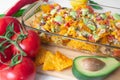 Baked nacho dish in a glass baking pan with corn tortilla chip, pico de gallo salsa, avocado guacamole chipotle, beans, jalapenos Royalty Free Stock Photo