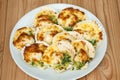 Baked parmesan scallops in a white ceramic plate on a wooden table . Oven baked scallop with cheese, spinach, butter and garlic Royalty Free Stock Photo