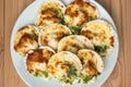 Baked parmesan scallops in a white ceramic plate on a wooden table . Oven baked scallop with cheese, spinach, butter and garlic Royalty Free Stock Photo