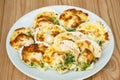 Baked parmesan scallops in a white ceramic plate on a wooden table . Oven baked scallop with cheese, spinach, butter and garlic Royalty Free Stock Photo