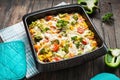 Baked pasta with broccoli and cheesy tomato sauce on wood background