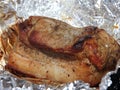 Baked piece of pork meat on aluminum foil, the process of cooking meat dishes in the oven.