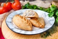 Baked pies with meat on a plate on a background of vegetables