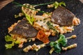 Baked plaice fillet with vegetables and sauce close-up on a bla Royalty Free Stock Photo