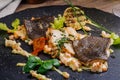 Baked plaice fillet with vegetables and sauce close-up on a bla Royalty Free Stock Photo