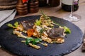 Baked plaice fillet with vegetables and sauce close-up on a black stone plate Royalty Free Stock Photo