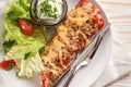 Baked pointed bell pepper stuffed with rice, tuna, tomatoes and cheese on a white plate with lettuce salad and dip, close up shot Royalty Free Stock Photo