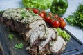 Baked pork chopped in a walnut and mint sauce on a cutting board with fresh herbs and vegetables. Light background