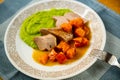 Baked pork tenderloin with orange pumpkin piece and fresh green pea porridge on plate with fork Royalty Free Stock Photo