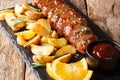 Baked pork tenderloin with rosemary in honey-orange sauce served with potato wedges closeup on a plate. horizontal Royalty Free Stock Photo