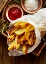 Baked potato fries, wedges with addition sea salt and rosemary on a wooden background, top view. Royalty Free Stock Photo