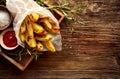 Baked potato fries, wedges with addition sea salt and rosemary on a wooden background, top view. Royalty Free Stock Photo