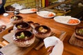 Baked potatoes in ceramic pots with sauce and cheese on wooden board on the background of a restaurant kitchen and