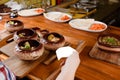 Baked potatoes in ceramic pots with sauce and cheese on wooden board on the background of a restaurant kitchen and