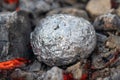 baked potatoes in foil in hot coals close up