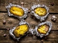 Baked potatoes in foil on a wooden table .