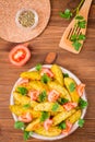 Baked potatoes in a peel with tomatoes in a plate and herbs