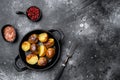 Baked potatoes , in frying cast iron pan, on black dark stone table background, top view flat lay, with copy space for text Royalty Free Stock Photo