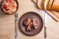 Baked potatoes with slices of bacon and eating utensils on wooden background. Sauerkraut in clay bowl and slices of white bread o Royalty Free Stock Photo