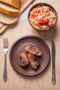 Baked potatoes with slices of bacon and eating utensils on wooden background. Sauerkraut in clay bowl and slices of white bread o Royalty Free Stock Photo