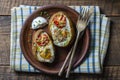 Baked potatoes stuffed with cheese, tomato, green onion and eggs in ceramic plate on wooden background, top view, closeup Royalty Free Stock Photo