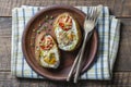 Baked potatoes stuffed with cheese, tomato, green onion and eggs in ceramic plate on wooden background, top view, closeup Royalty Free Stock Photo