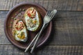 Baked potatoes stuffed with cheese, tomato, green onion and eggs in ceramic plate on wooden background, top view, closeup Royalty Free Stock Photo