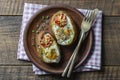 Baked potatoes stuffed with cheese, tomato, green onion and eggs in ceramic plate on wooden background, top view, closeup Royalty Free Stock Photo