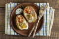 Baked potatoes stuffed with cheese, tomato, green onion and eggs in ceramic plate on wooden background, top view, closeup Royalty Free Stock Photo