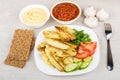 Baked potatoes with tomatoes, cucumbers, bowl with ketchup and m