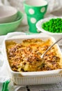 Baked pudding with fish and mushrooms in a ceramic form for roasting and green peas in a bowl. Royalty Free Stock Photo