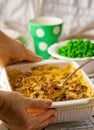 Baked pudding with fish and mushrooms in a ceramic form for roasting and green peas in a bowl.