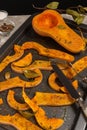 Baked pumpkin slices with spices and bay leaves on a dark baking sheet. Selective focus