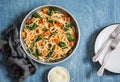 Baked pumpkin and spinach spaghetti in a frying pan on wooden table, top view. Delicious lunch in a mediterranean style.