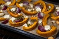 Baked pumpkin or squash slices with red onions, garlic, feta cheese and thyme on a tray, autumn vegetables for a Thanksgiving and