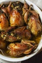 Baked quail stuffed with mushrooms, eggs and bread in a ceramic form on a wooden table.