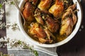 Baked quail stuffed with mushrooms, eggs and bread in a ceramic form on a wooden table.