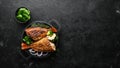 Baked red fish perch with vegetables on a black stone plate. Top view.