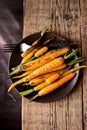 Baked Roasted Raw Freah Carrots with Olive Oil and Spices Lying on Plate Top View Horizontal Healthy Diet Organic Food Wooden