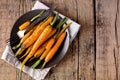 Baked Roasted Raw Freah Carrots with Olive Oil and Spices Lying on Plate Top View Horizontal Healthy Diet Organic Food Wooden