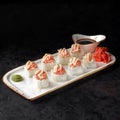 Baked roll with salmon. Roll with curd cheese, cucumber, avocado and baked salmon cap with Tobiko caviar with sauce. Royalty Free Stock Photo