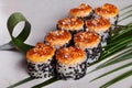 Baked roll with sesame seeds and black hat, tropical leaves, still life, Japanese cuisine