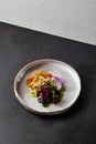 Baked root vegetables in handmade ceramic dishware. Vegan food - caramelized carrot, beetroot and celery on modern crockery.