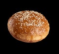 Baked round bun with sesame seeds isolated on black background