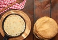 Baked round thin pancakes lie stacked on a wooden board, brown table