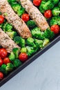 Baked salmon fillet with broccoli and tomato on frying tray, vertical, top view Royalty Free Stock Photo